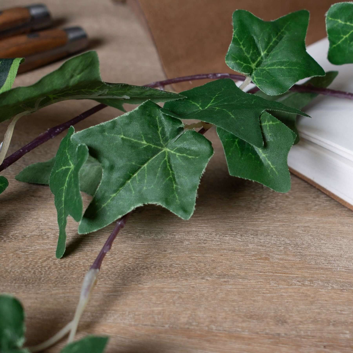 Ivy Garland featuring realistic green leaves on a wooden surface, perfect for decoration and trade displays.